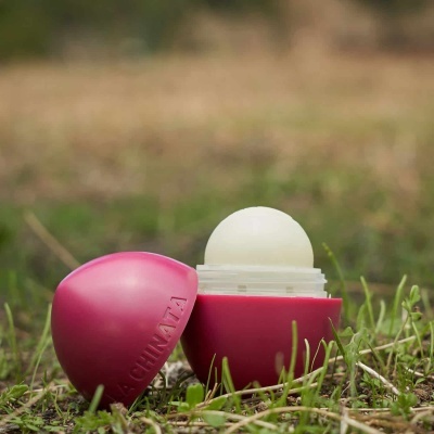 Bálsamo labial esférico rosa aberto na relva