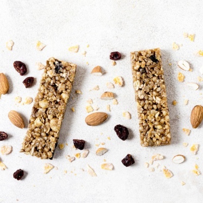 Duas barritas de cereais com amêndoas e frutos secos sobre superfície clara