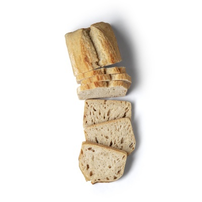Loaf of rustic bread partially sliced on white background