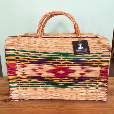 Mala de mão artesanal em palha com padrão colorido e etiqueta Maracatu de Olinda