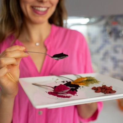 Mulher a segurar prato com cinco montes de pó colorido e colher na mão