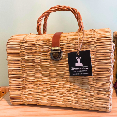 Bolsa de mão de palha trançada com alça torcida e fecho metálico, com etiqueta preta