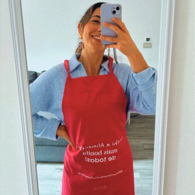 Mulher com avental vermelho com texto branco num ambiente interior moderno