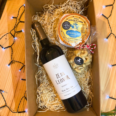Caixa de oferta com vinho tinto, queijo curado e frutos secos em embalagem de cartão