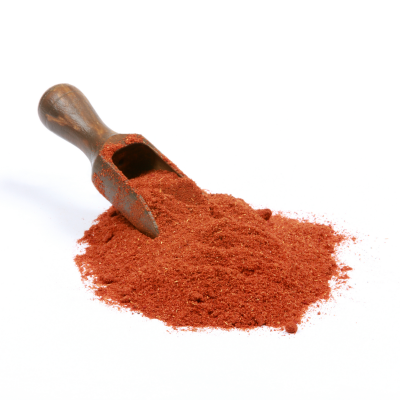 Pá de madeira com pó vermelho alaranjado sobre fundo branco