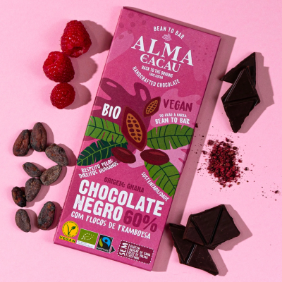 Barra de chocolate negro 60% com flocos de framboesa em embalagem rosa e elementos naturais