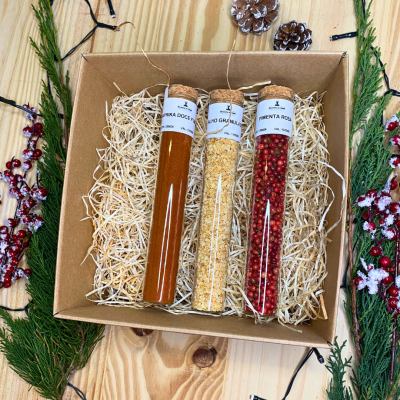 Conjunto de três tubos de ensaio com especiarias numa caixa de cartão sobre superfície de madeira clara