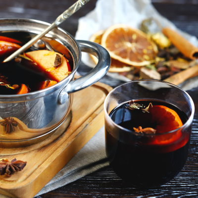 Copo e tacho com bebida quente e especiarias em fundo escuro