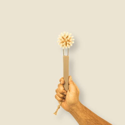 Mão segurando escova de limpeza com cabo bege e cerdas claras