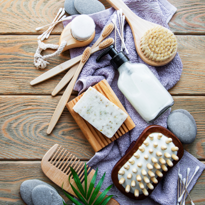 Produtos de higiene pessoal e beleza, incluindo escovas, sabão, frasco e toalha sobre madeira