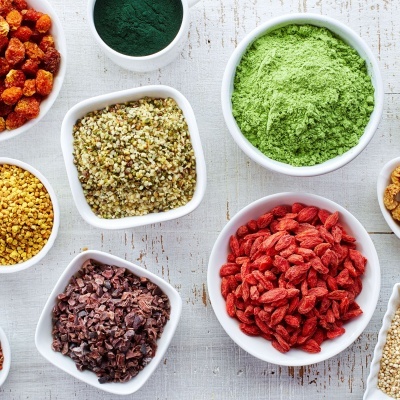 Tigelas brancas com superalimentos variados sobre superfície branca