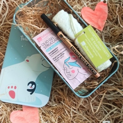 Caixa metálica azul com produtos de beleza sobre palha e corações cor-de-rosa.