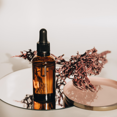 Frasco âmbar com conta-gotas em espelho com ramos secos