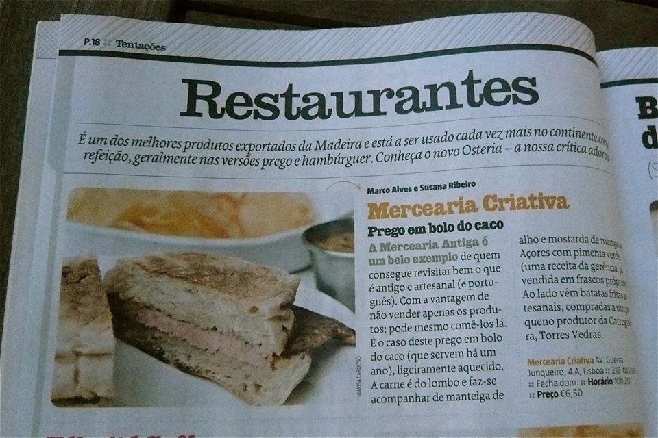 Dois pães tipo bolo do caco sobre um prato numa página de jornal com artigo 'Restaurantes'