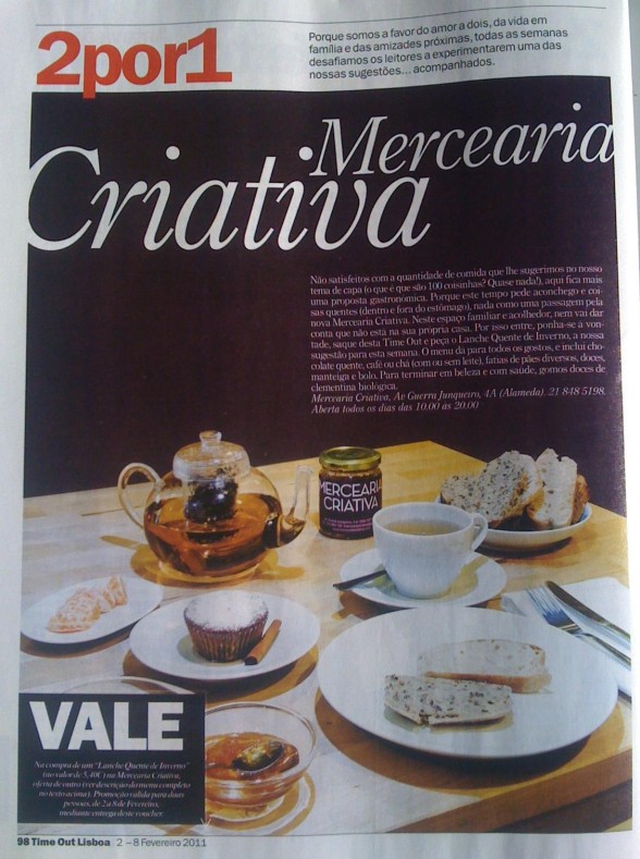 Mesa com chávena, bule de vidro, pote rotulado 'MERCEARIA CRIATIVA', pão com sementes, cupcake e texto publicitário em português.