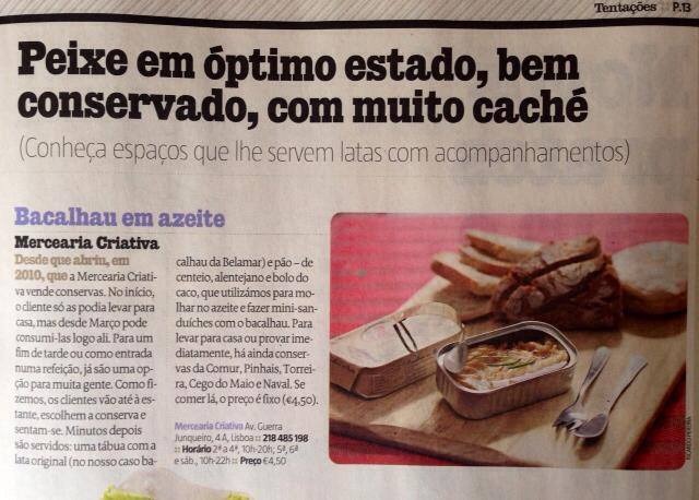 Lata aberta de bacalhau em azeite com pão e queijo sobre tábua de madeira