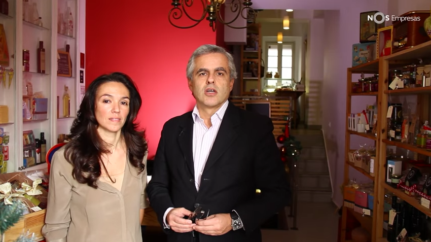 Duas pessoas em loja com prateleiras cheias de produtos e escadaria ao fundo