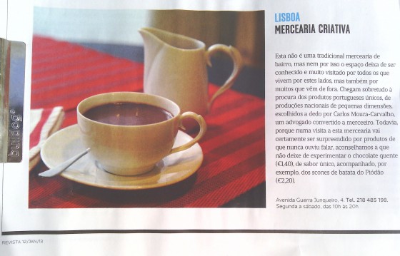 Chávena branca com café e jarro branco sobre tecido xadrez vermelho e preto