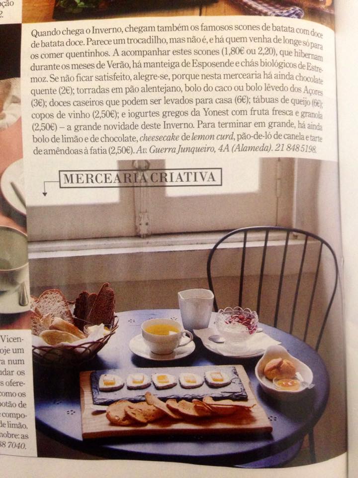 Mesa azul com chávenas, doces e pão, interior junto a janela