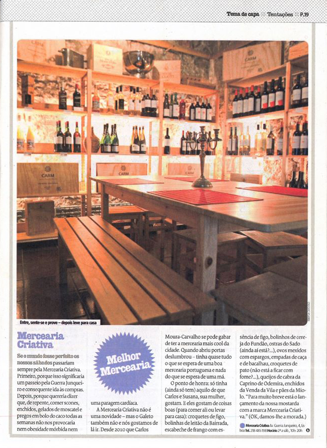 Sala de armazenamento e degustação de vinhos com prateleiras em madeira, mesa, bancos e castiçal