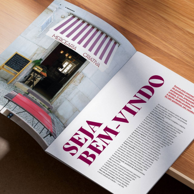 Página de revista aberta com texto e imagem de entrada de loja Mercearia Criativa com toldo roxo e branco
