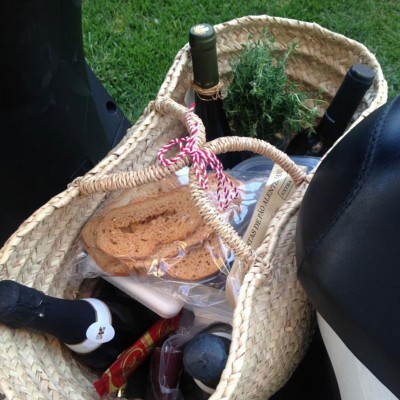 Cesta de palha com vinho, pão, ervas e chocolates