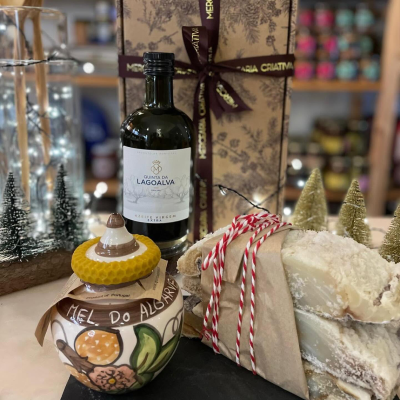 Conjunto de azeite, mel e queijo em ambiente decorado com árvores pequenas e luzes.