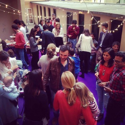 Evento social com várias pessoas e chão roxo, luzes de corda no teto