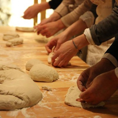 Mãos a moldar massa de pão numa superfície de madeira