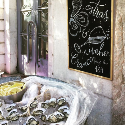 Ostras frescas em gelo com limão e placa promocional de vinho branco na parede