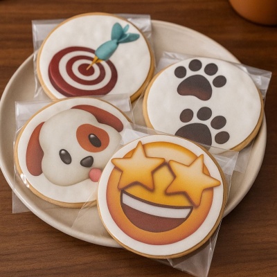 Bolachas decoradas com diferentes desenhos coloridos, em embalagem individual, num prato branco sobre mesa de madeira