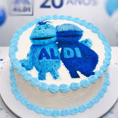 Bolo redondo decorado com personagens azuis e palavra ALDI em creme