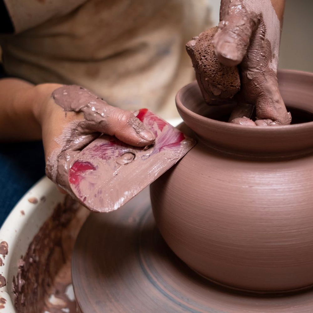Vaso de barro em processo de moldagem manual num torno de oleiro