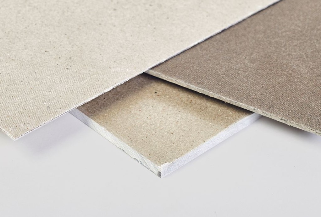 Placa Rígida de Mica Moscovite Três placas de gesso cartonado empilhadas em tons bege e cinzento.