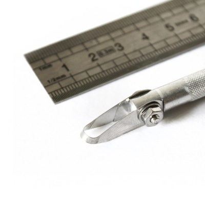 ferramenta metálica com lâmina curva ao lado de régua de metal