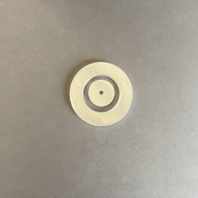 Disco circular branco com dois anéis sobre superfície cinza