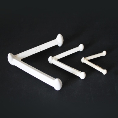 Três ganchos brancos de tamanhos diferentes sobre fundo preto