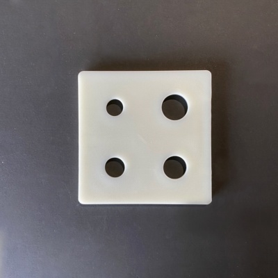 Dado branco plástico com quatro buracos circulares sobre superfície preta
