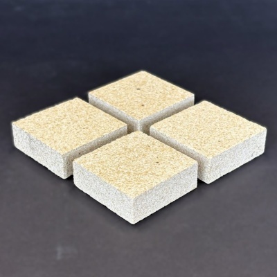 Quatro blocos quadrados de pedra bege rugosa sobre fundo escuro