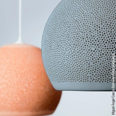 Dois candeeiros pendentes com padrão de pequenos furos, um cinza azulado e outro laranja suave