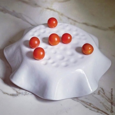 Fruteira branca ondulada em cerâmica com tomates cereja vermelhos