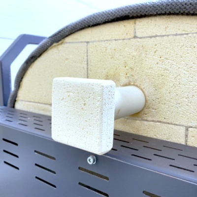 Parte de forno de pizza refratário com tubo branco e prateleira metálica preta