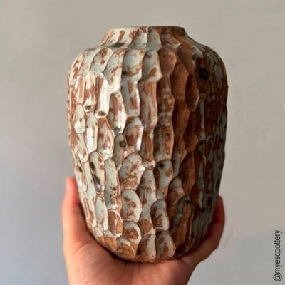 Vaso cerâmico texturizado castanho e bege numa mão