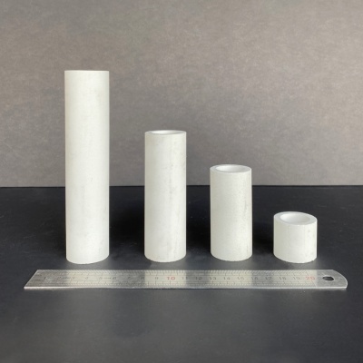 Quatro tubos cónicos brancos de alturas e diâmetros variados com régua metálica na frente