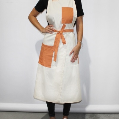 Avental comprido claro com bolsos e cinto laranja usado por pessoa.