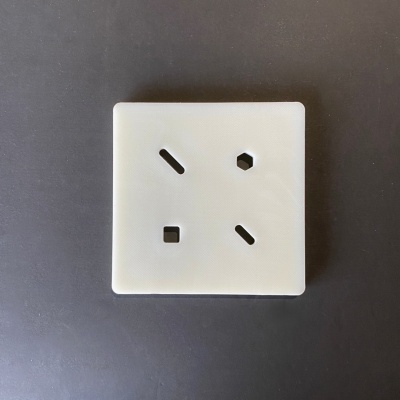 Tomada elétrica branca com três buracos em formatos diferentes num fundo cinza-escuro