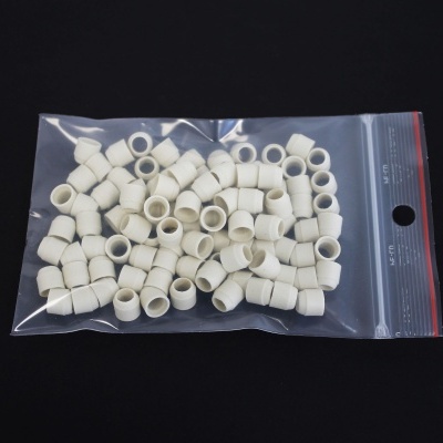 Pacote com peças pequenas brancas cilíndricas em fundo preto.