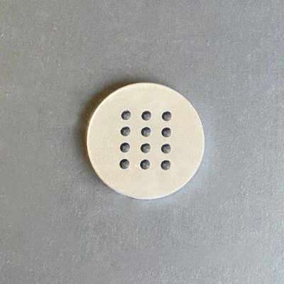 Botão branco redondo com doze furos sobre fundo cinza