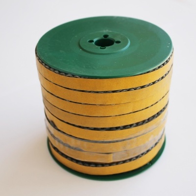 Rolo de fita adesiva amarela com linhas pretas e extremidades verdes