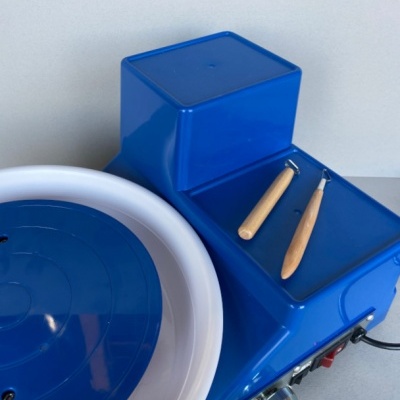 Máquina de cerâmica azul com recipiente branco e ferramentas de madeira